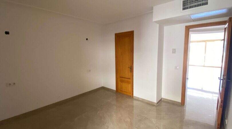 Leerer Wohnraum mit Marmorboden, Holztüren und Zugang zur Terrasse in Hafenwohnung Porto Cristo