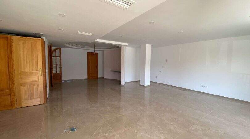 Leerer Wohnbereich mit Marmorböden, Holztüren und Deckenverkleidung in Hafenwohnung Porto Cristo