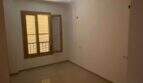 Leeres Zimmer der Hafenwohnung Porto Cristo mit Fliesenboden, weißen Wänden und Holzfenster mit Jalousie