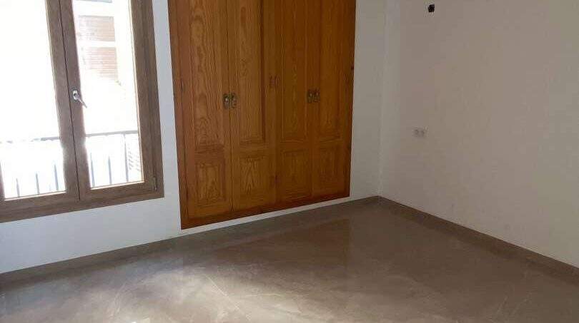 Leeres Schlafzimmer mit Marmorböden, Holzeinbauschrank und Fenster mit Balkonblick in Porto Cristo