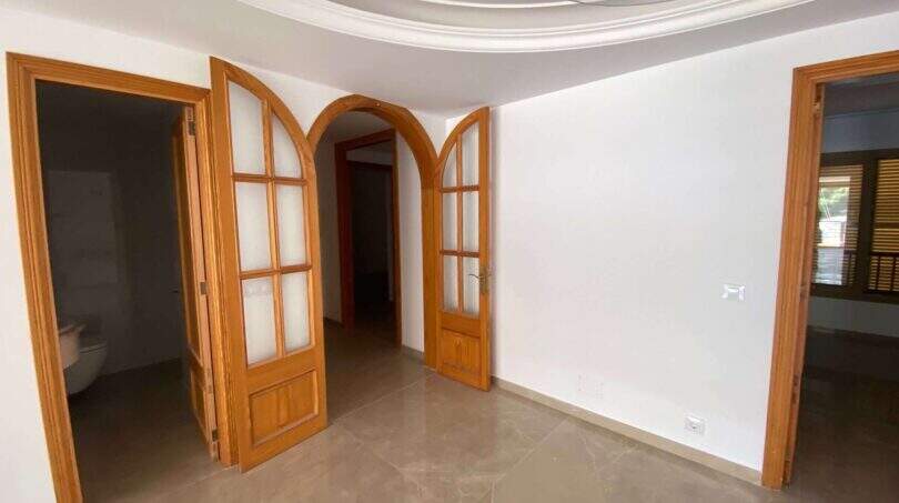 Leerer Wohnraum mit eleganten Rundbogen-Holztüren und hellem Marmorboden in exklusiver Hafenwohnung Porto Cristo