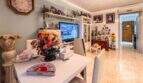 Wohnzimmer der Wohnung in Palma mit TV-Wand, Esstisch, Blumendeko und Familienfotos an der Wand.
