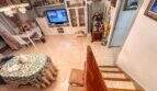 Wohnzimmer mit Treppenblick, weißem TV-Möbel, Esstisch und Fliesenboden in strandnaher Palma-Wohnung