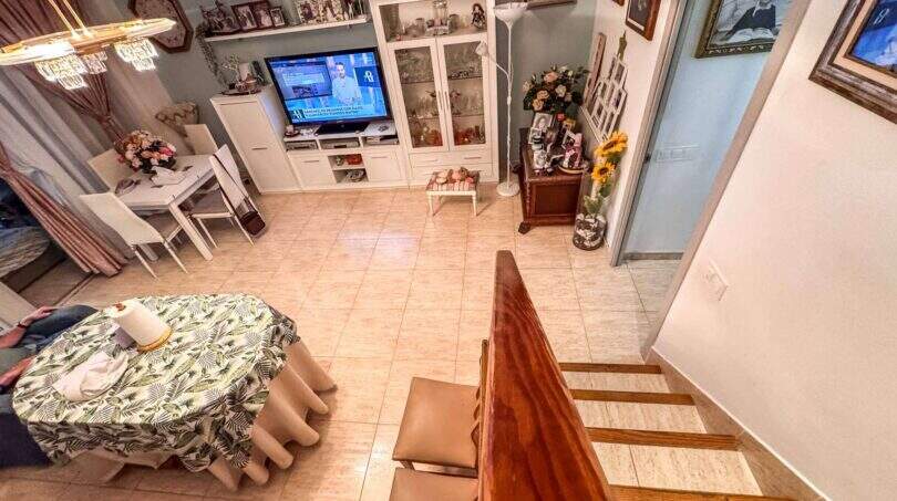 Wohnzimmer mit Treppenblick, weißem TV-Möbel, Esstisch und Fliesenboden in strandnaher Palma-Wohnung