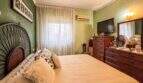 Schlafzimmer mit Doppelbett, Holzkommode, TV und Klimaanlage in strandnaher Wohnung in Palma de Mallorca.