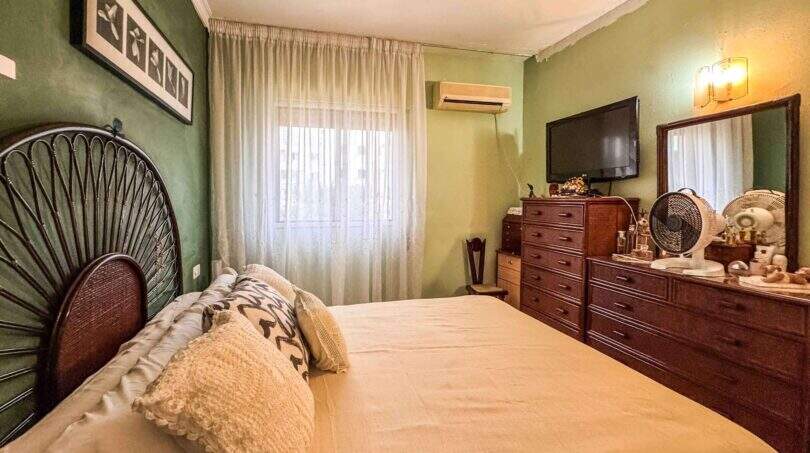 Schlafzimmer mit Doppelbett, Holzkommode, TV und Klimaanlage in strandnaher Wohnung in Palma de Mallorca.