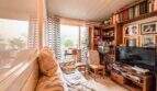 Gemütliches Wohnzimmer mit Bücherregal, TV und Fensterfront mit Gartenblick in strandnaher Palma-Wohnung