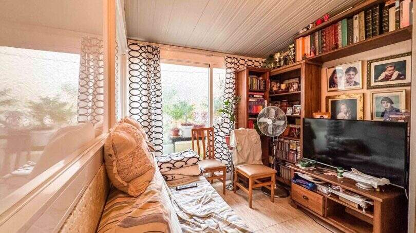 Gemütliches Wohnzimmer mit Bücherregal, TV und Fensterfront mit Gartenblick in strandnaher Palma-Wohnung