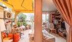 Überdachte Terrasse mit Pflanzen und Blick ins Wohnzimmer mit Bücherregal, Wohnung in Palma de Mallorca