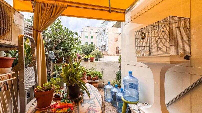 Überdachte Terrasse mit Markise, Zimmerpflanzen und Blick auf den Innenhof der Wohnung in Palma de Mallorca.