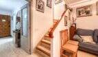 Eingangsbereich mit Holztreppe, Familienfotos, Sofa und Holztür in strandnaher Wohnung in Palma de Mallorca.