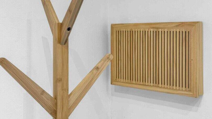 Holzgarderobe im Baumdesign und Holzlüftungsgitter an weißer Wand im modernen Stadthaus Felanitx