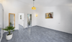 Helles Wohnzimmer mit grauem Fliesenboden, Pendelleuchte, Stiergemälde und Palme in Felanitx
