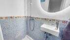 Modernes Bad mit blauem Mosaikfliesenspiegel, buntem Bordürendekor, Handbrause und elegantem Wandwaschbecken