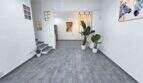 Helles Wohnzimmer mit grauem Fliesenboden, Treppe, tropischen Pflanzen und modernen Kunstwerken an weißen Wänden