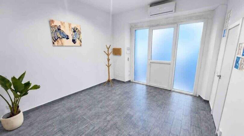 Heller Eingangsbereich mit grauem Fliesenboden, Klimaanlage, Glastür und Zebra-Wandbild in modernem Stadthaus Felanitx