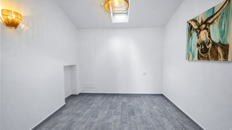 Leerer Wohnraum mit grauem Fliesenboden, Wand-Eselgemälde, Skylight und Rattanlampen im modernen Stadthaus Felanitx