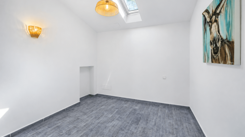 Helles, leeres Zimmer mit Dachfenster, Pendelleuchte, Wandlampe und Esel-Kunstwerk in modernem Stadthaus Felanitx