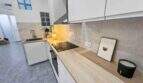 Moderne weiße Einbauküche mit Holzarbeitsplatte, Induktionskochfeld und Glasziegel-Rückwand im Stadthaus Felanitx