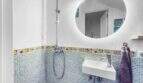 Modernes Badezimmer mit blauem Mosaikfliesen, buntem Bordürendekor, Regendusche und beleuchtetem Rundspiegel in Stadthaus Felanitx