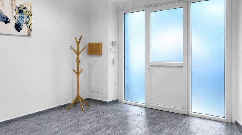 Heller Eingangsbereich mit Granitboden, Holzgarderobe, Zebra-Kunstwerk und großer Glastür mit Klimaanlage