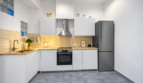 Moderne weiße Küche mit Holzarbeitsplatte, Einbauofen, Edelstahlkühlschrank und Glasbausteinfen in Felanitx