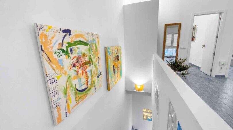 Heller Treppenaufgang mit abstrakten Gemälden, weißen Wänden und modernem Design im Stadthaus Felanitx