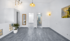 Helles Wohnzimmer mit grauem Fliesenboden, weißen Wänden, Designerlampen und Blick auf Bad in modernem Stadthaus Felanitx