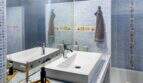 Modernes Badezimmer mit blauem Mosaikfliesenspiegel, zwei Aufsatzwaschbecken und bunten Akzentfliesen im Stadthaus Felanitx