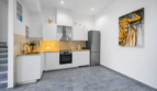 Moderne weiße Küche mit Holzarbeitsplatte, Edelstahlkühlschrank und Stiergemälde im Stadthaus Felanitx