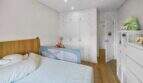 Bright children's room with wooden floor, white built-in wardrobe, bed with safety rail and dresser in Felanitx