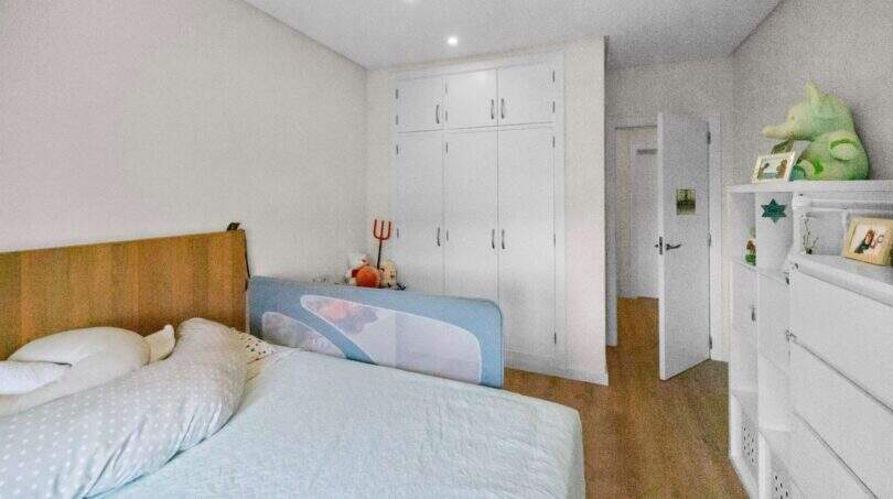 Bright children's room with wooden floor, white built-in wardrobe, bed with safety rail and dresser in Felanitx