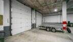 Spacious garage with two sectional doors and a trailer in a house in Felanitx.