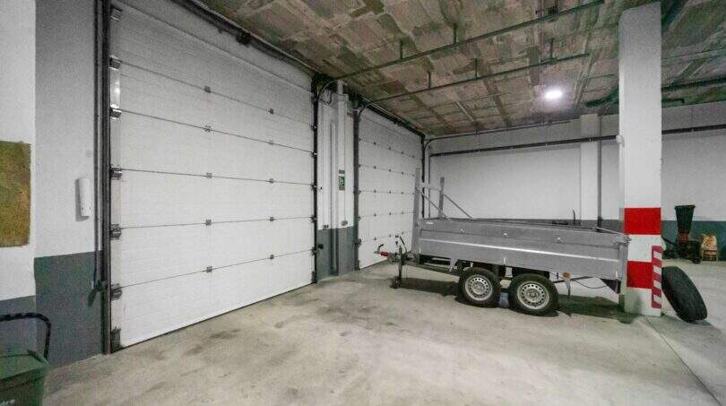 Spacious garage with two sectional doors and a trailer in a house in Felanitx.