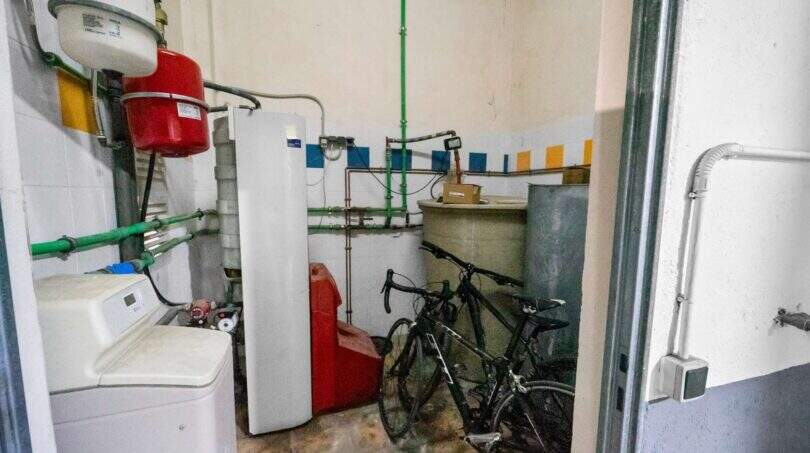 Utility room with washing machine, heating system, green pipes and bicycles in house in Felanitx