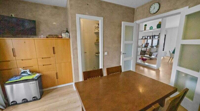 Dining room with wooden table, built-in wardrobe and passage to living area in house in Felanitx