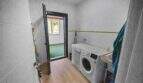 Utility room with washing machine, wooden floor and door to outdoor area in Felanitx