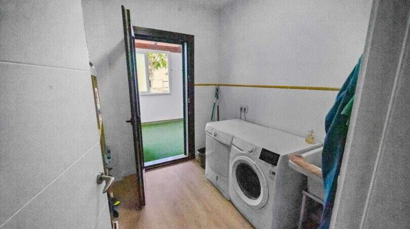 Utility room with washing machine, wooden floor and door to outdoor area in Felanitx