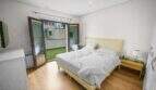 Bright bedroom with double bed, wooden floor and glass sliding door to terrace in house Felanitx