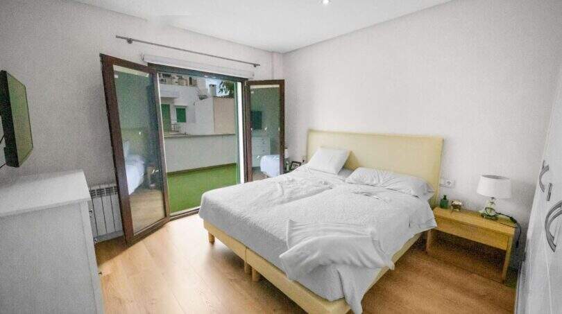 Bright bedroom with double bed, wooden floor and glass sliding door to terrace in house Felanitx