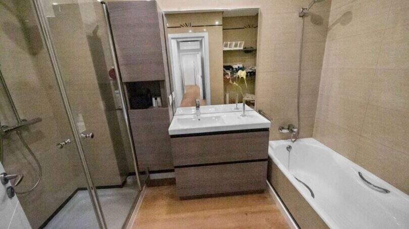 Modern bathroom with glass shower, built-in wardrobe, double sink and bathtub in house in Felanitx
