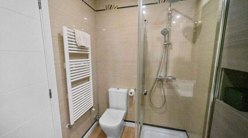 Modern bathroom with glass shower, toilet and towel radiator in house in Felanitx