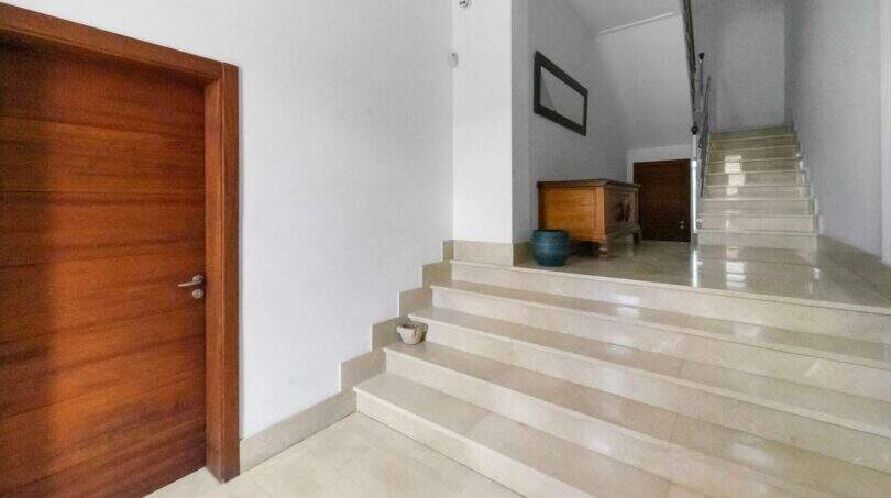 Bright stairwell with marble staircase, wooden door and wooden dresser in the house in Felanitx