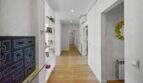 Bright, long hallway with wooden floor, built-in shelves and white walls in the spacious house in Felanitx
