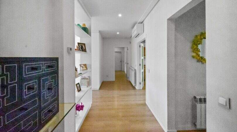 Bright, long hallway with wooden floor, built-in shelves and white walls in the spacious house in Felanitx