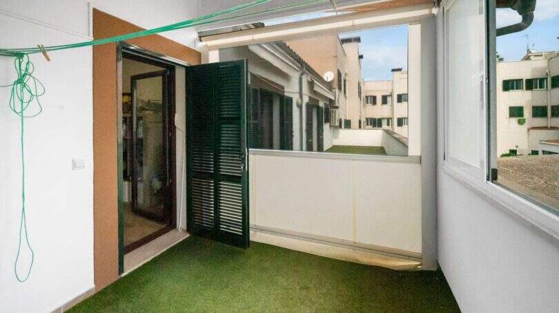 Covered balcony with artificial grass, green shutters and view of inner courtyard in Felanitx