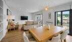 Bright living-dining room with wooden table, white chairs, sofa and balcony access in house in Felanitx