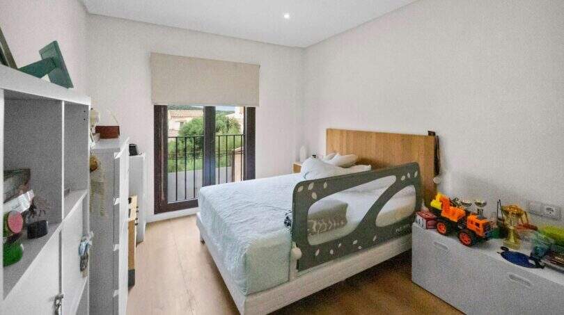 Children's room with single bed, bed guard rail, toys and balcony access with garden view in Felanitx