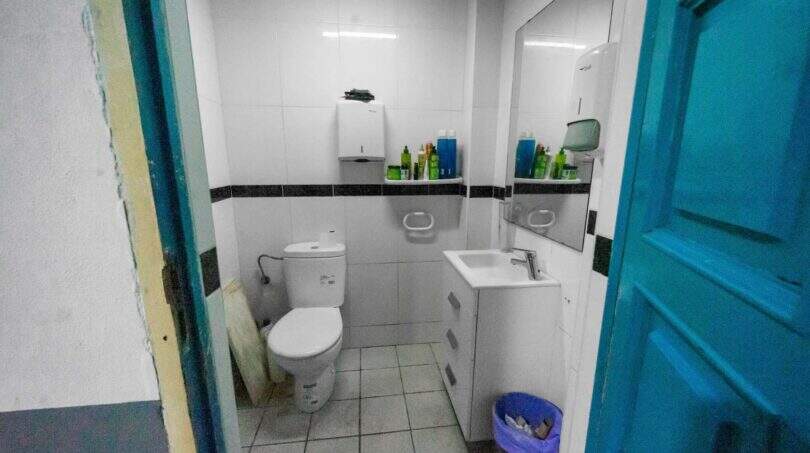 Small, white-tiled bathroom with toilet, sink, mirror and blue door in house in Felanitx.