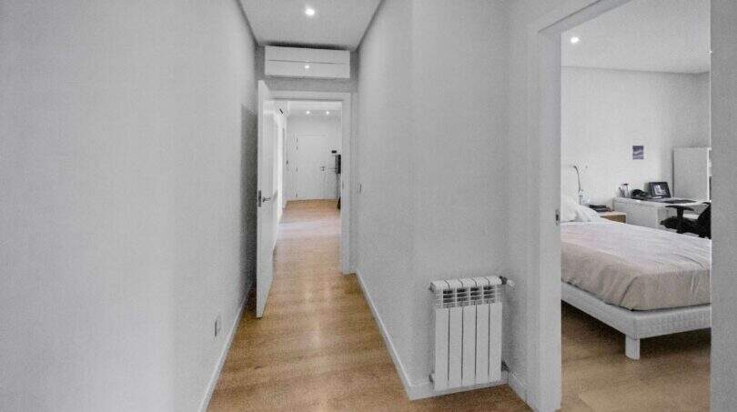 Bright hallway with wooden floor, radiator and view into modern bedroom in house in Felanitx